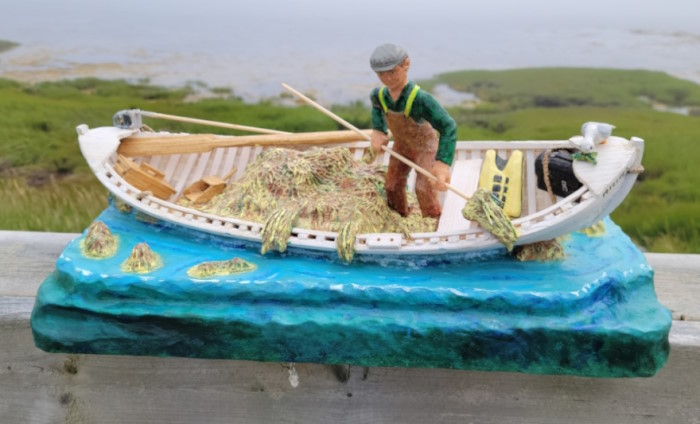 A fisherman harvesting seaweed in a skiff.